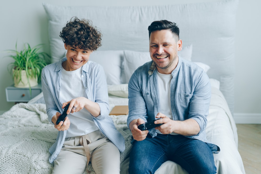 a man and a woman sitting on a bed playing a video game