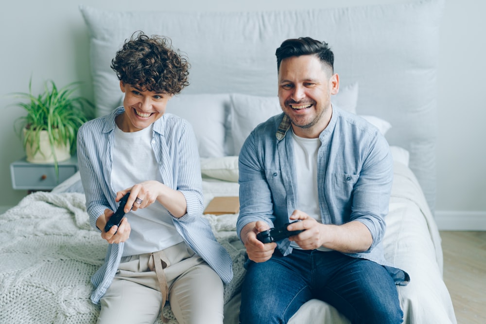 un uomo e una donna seduti su un letto che giocano a un videogioco