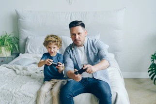 a man sitting on a bed next to a little boy