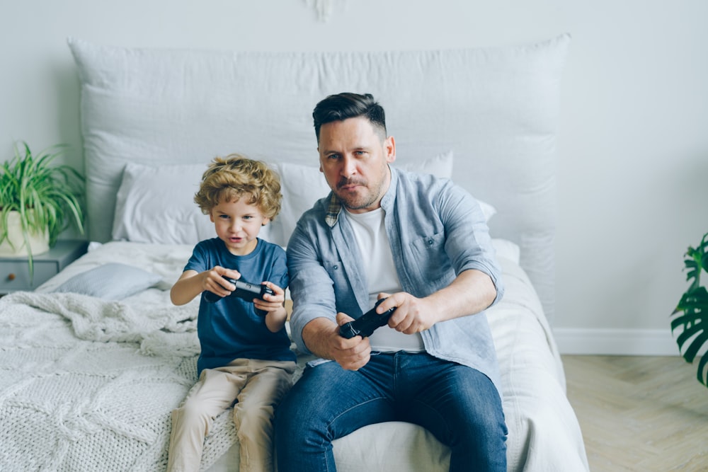 a man sitting on a bed next to a little boy