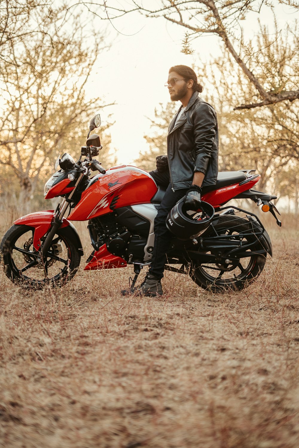 a man sitting on a red motorcycle in a field