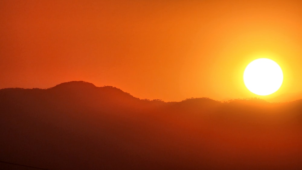 the sun is setting over a mountain range