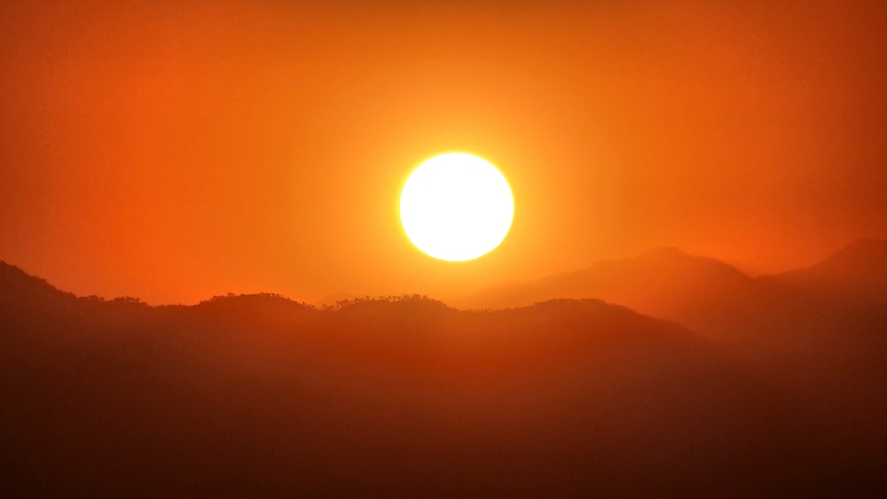 the sun is setting over a mountain range