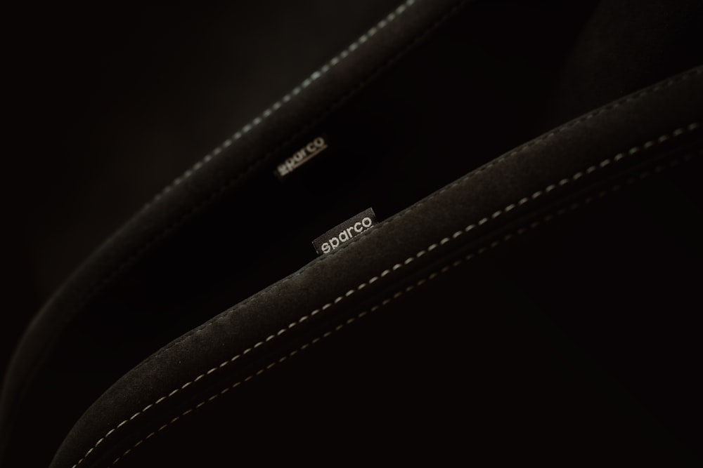 a close up of a black bag with white stitching
