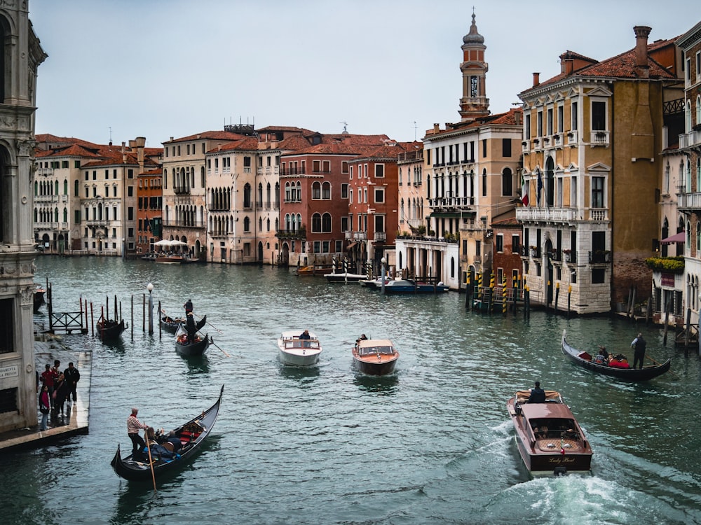 a group of boats floating down a river next to tall buildings