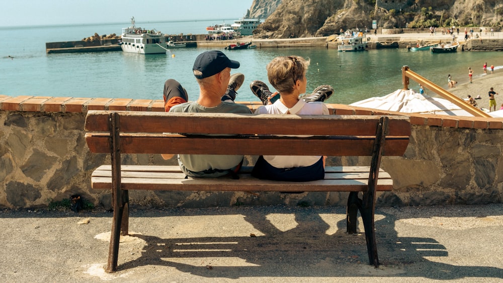 a couple of people sitting on a wooden bench