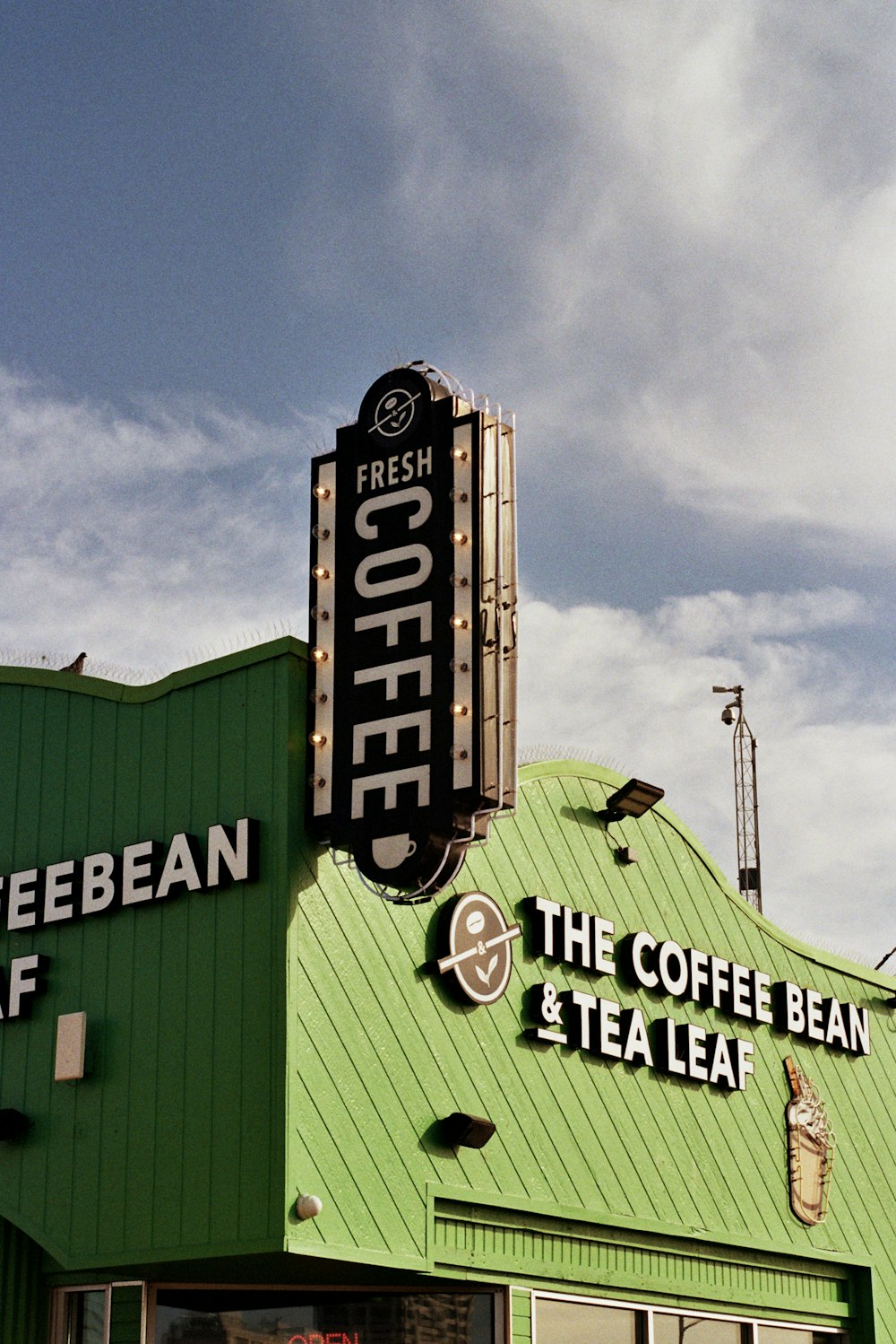 a green building with a sign that says fresh coffee and the coffee bean and tea