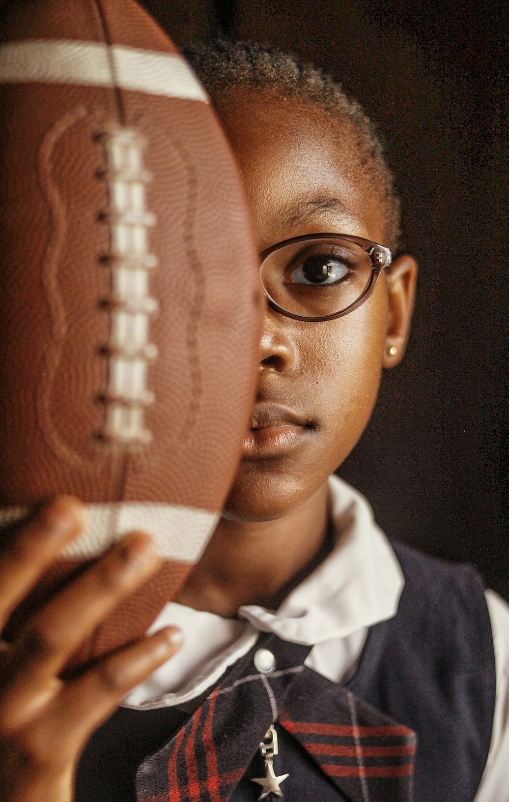 a girl in a school uniform holding a football