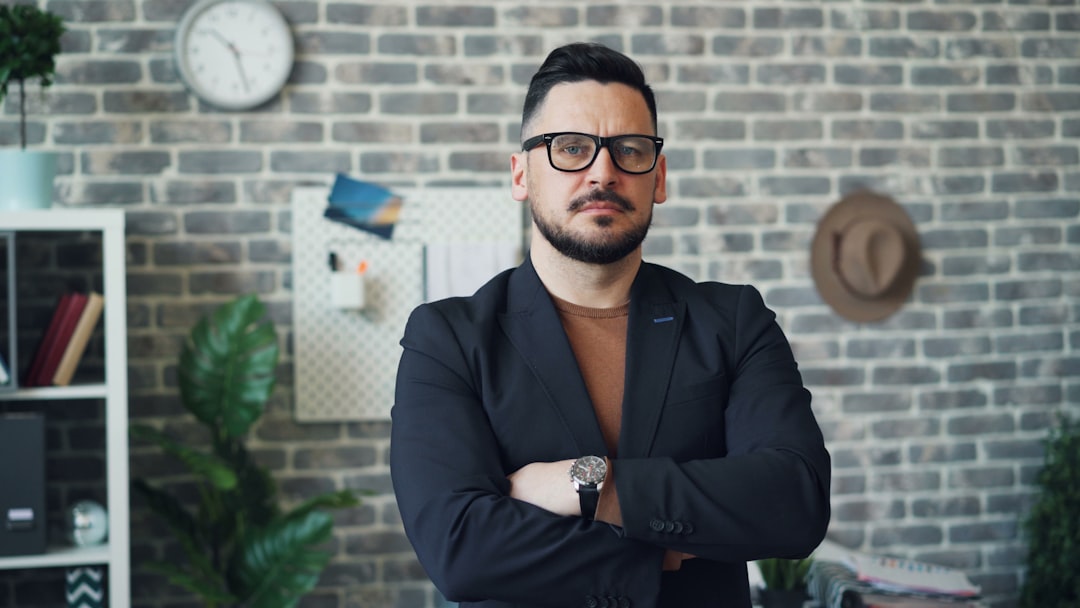 Portrait of serious independent guy standing at work in office with arms crossed