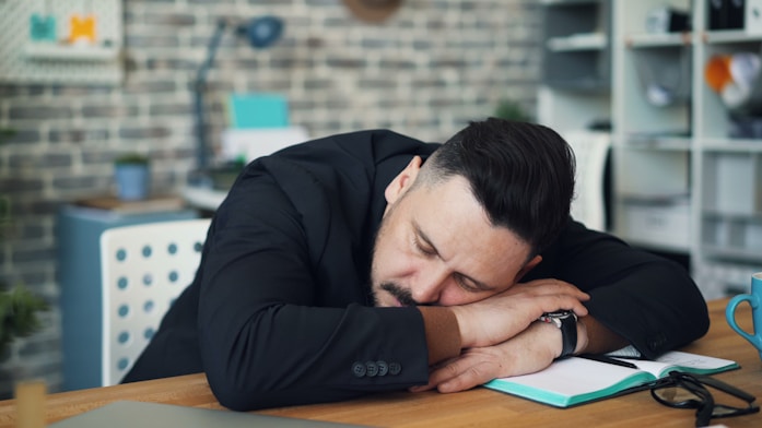 a man leaning his head on his desk