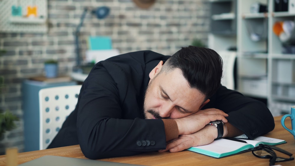 a man leaning his head on his desk