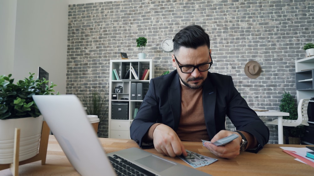 a man sitting at a table in front of a laptop