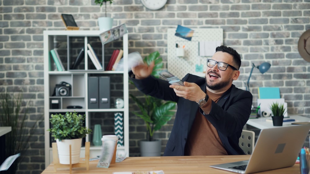 a man sitting at a desk holding a remote control