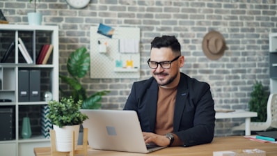a man sitting at a desk using a laptop computer