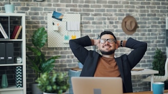 a man sitting at a desk with his hands behind his head