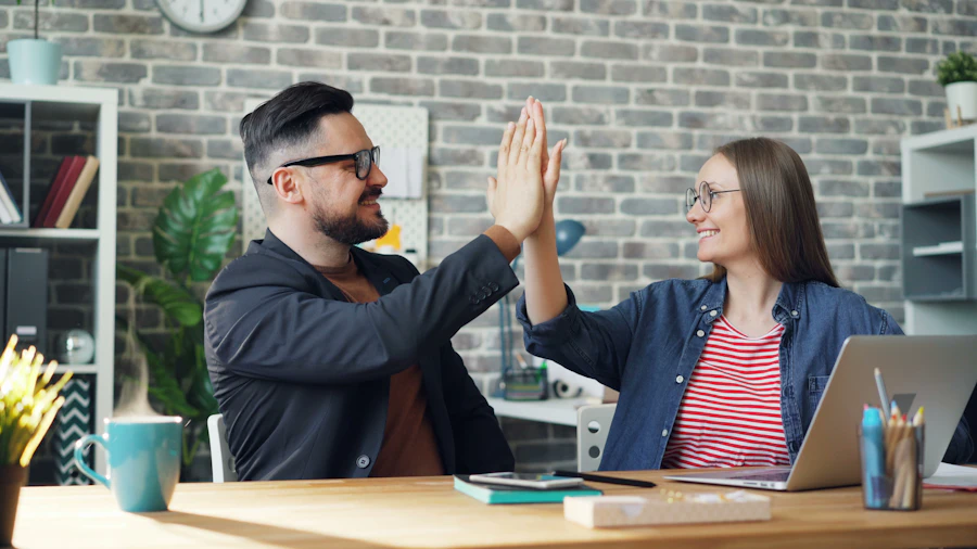 Deux membres d'une agence web se tapent dans la main devant un ordinateur portable