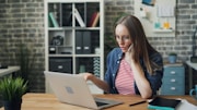 a woman sitting at a table using a laptop computer