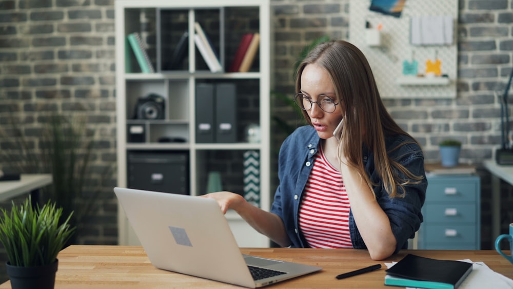 a woman sitting at a table using a laptop computer