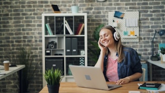 a woman sitting in front of a laptop computer wearing headphones