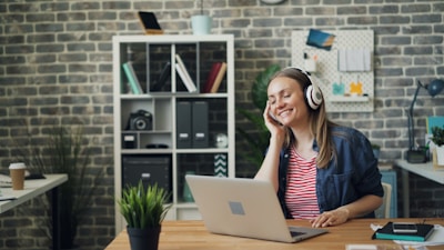 a woman sitting in front of a laptop computer wearing headphones