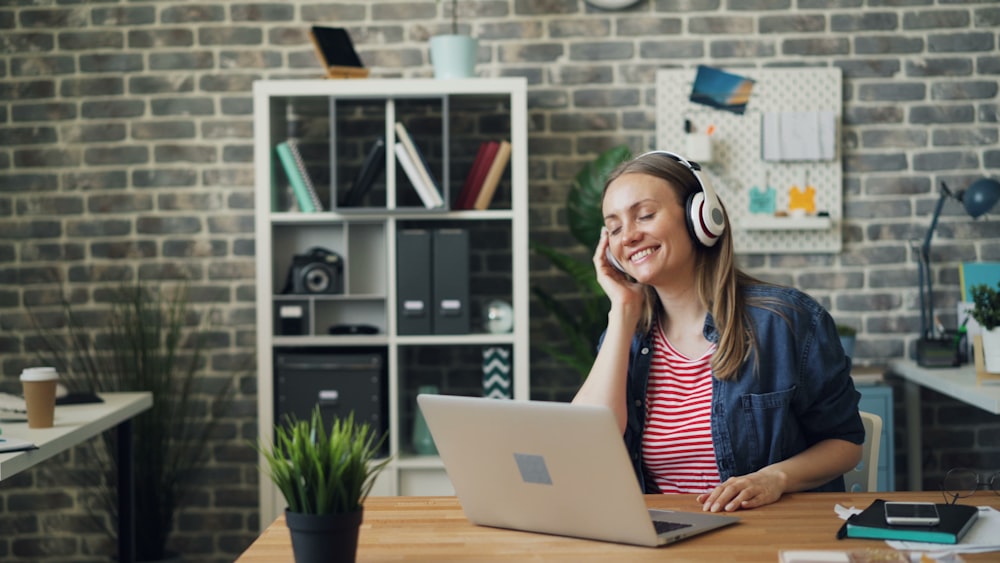 una donna seduta davanti a un computer portatile che indossa le cuffie