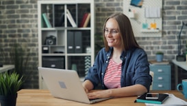a woman sitting at a table using a laptop computer