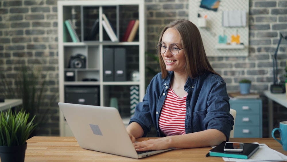 a woman sitting at a table using a laptop computer