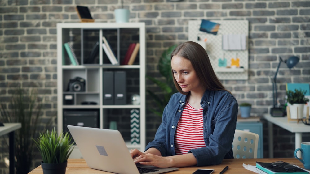 a woman sitting at a table using a laptop computer