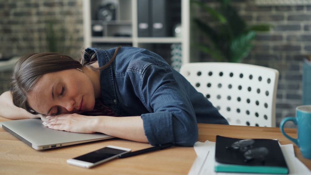 a woman laying her head on a laptop