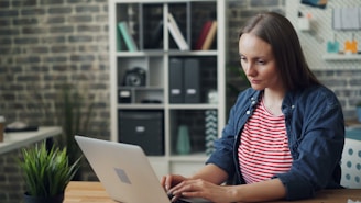 a woman sitting at a table using a laptop computer