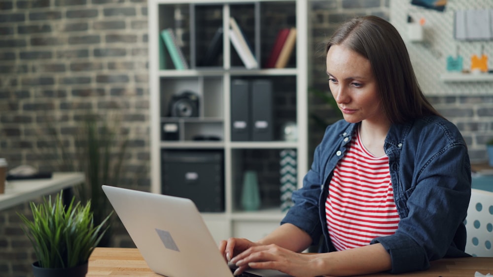 a woman sitting at a table using a laptop computer