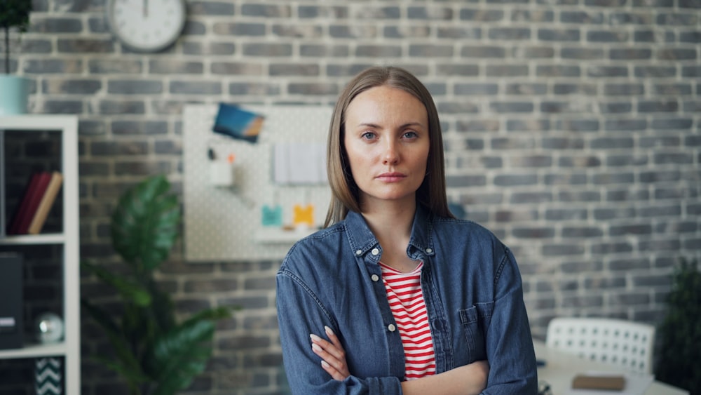 a woman standing in front of a brick wall