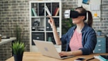 a woman using a laptop while wearing a virtual headset