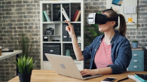 a woman using a laptop while wearing a virtual headset