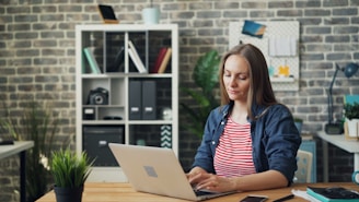 a woman sitting at a desk using a laptop computer