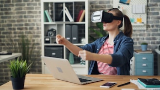 a woman using a laptop computer while wearing a virtual headset