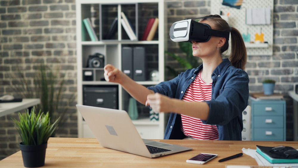 a woman using a laptop computer while wearing a virtual headset