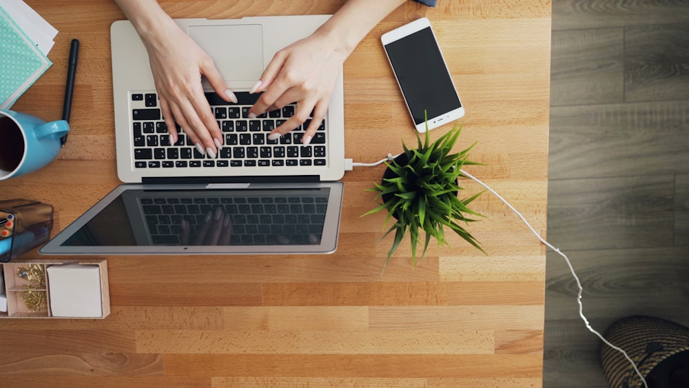 a person typing on a laptop on a wooden table