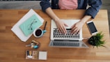 a woman sitting at a table working on a laptop