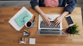 a woman sitting at a table working on a laptop
