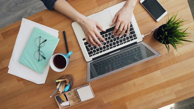 a person typing on a laptop on a wooden table