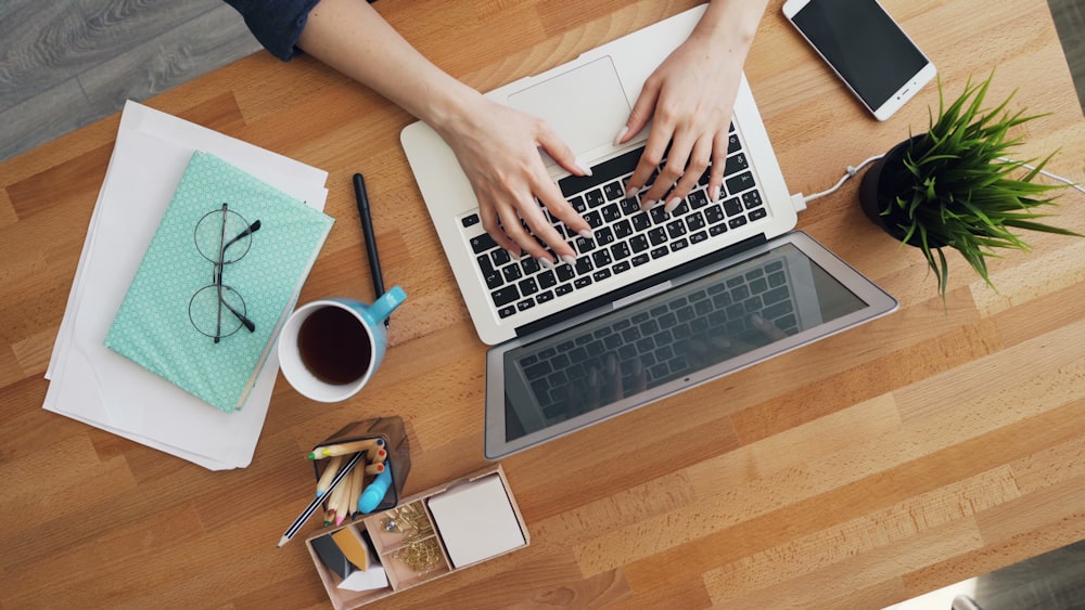 a person typing on a laptop on a wooden table