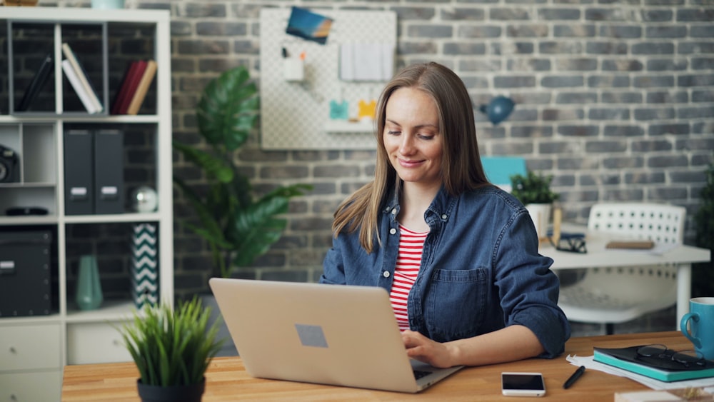 a woman sitting at a desk using a laptop computer