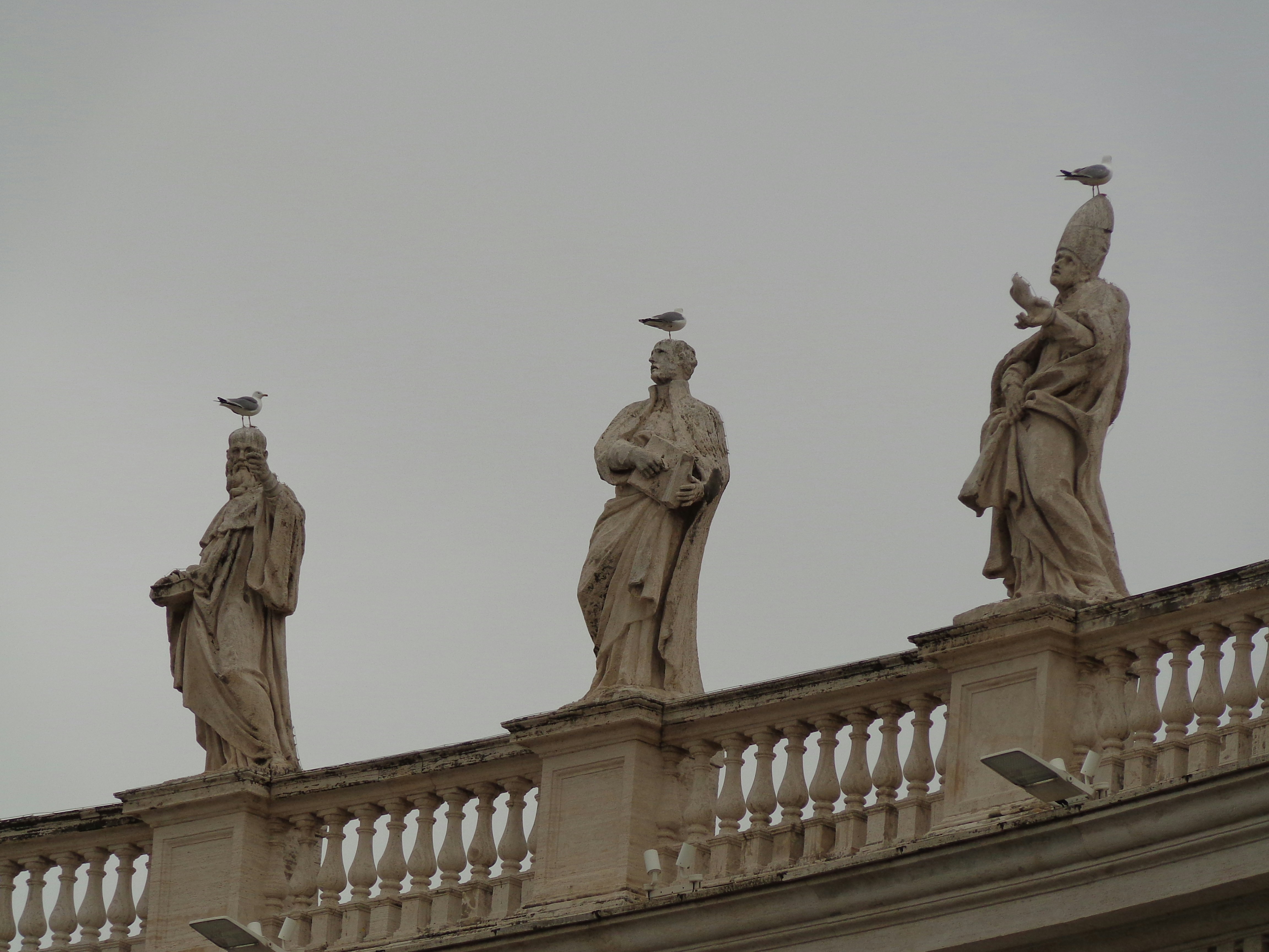 three statues on a balcony of a building