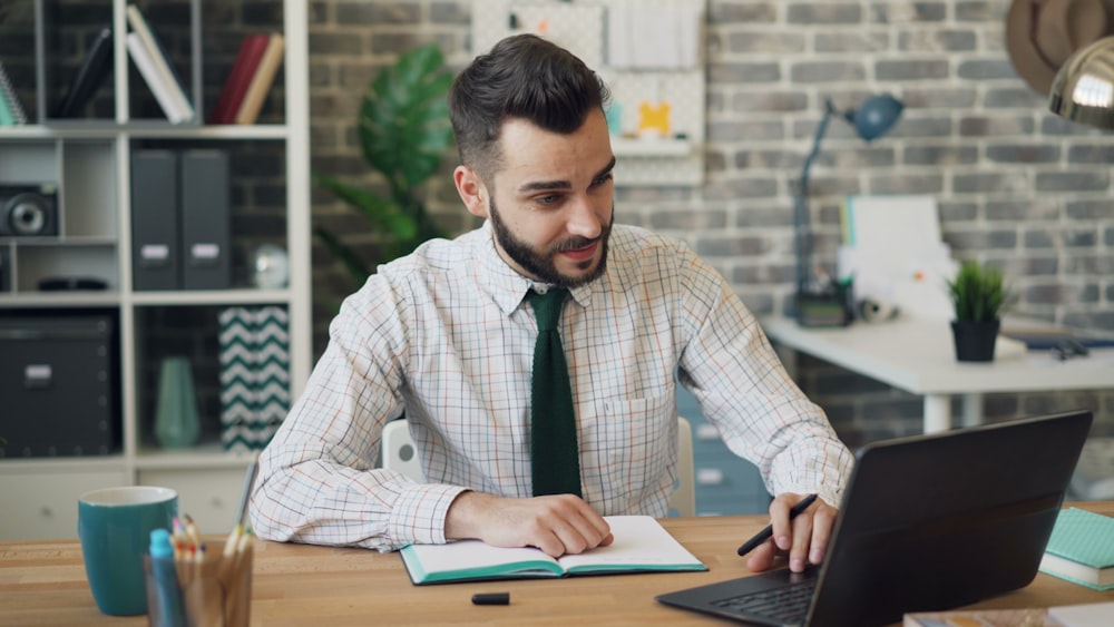 un uomo seduto a una scrivania che lavora su un laptop