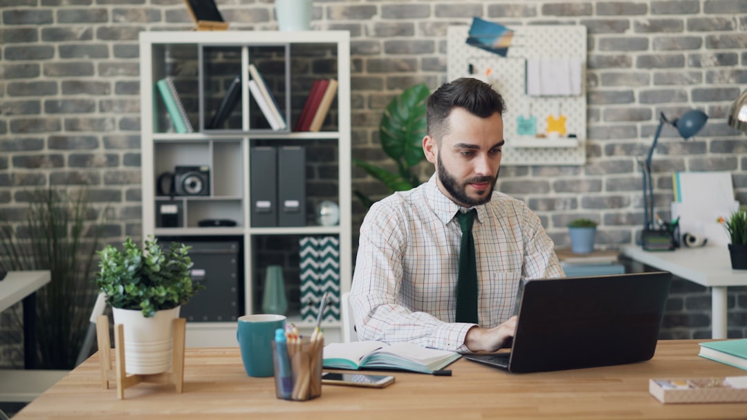 Happy employee using laptop then raising arms celebrating success in office