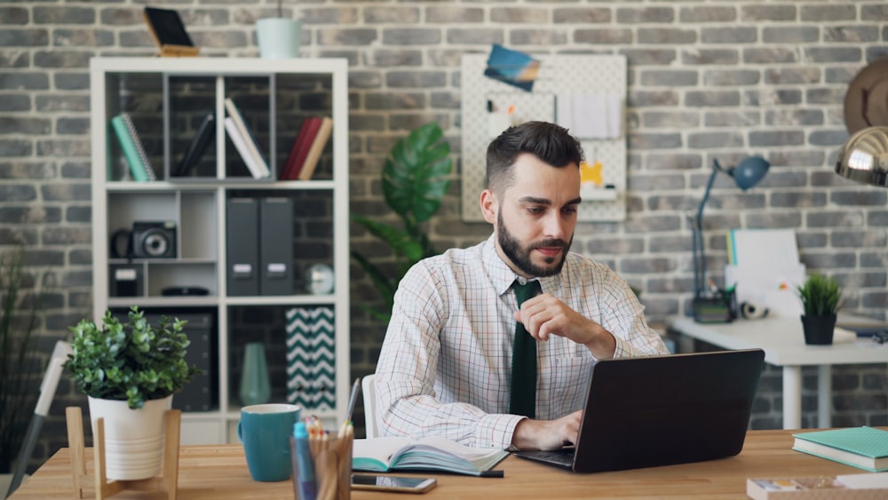 a man sitting at a desk using a laptop computer