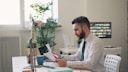 a man sitting at a desk with a laptop and papers