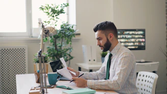 a man sitting at a desk with a laptop and papers