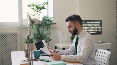 a man sitting at a desk with a laptop and papers